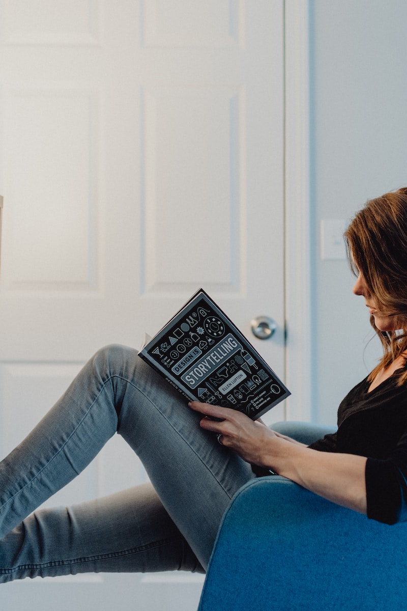 woman in black long sleeve shirt and blue denim jeans sitting on white table